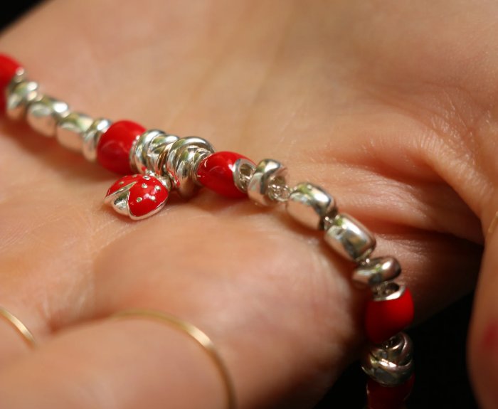 BRACCIALE RUBINIA FILODAMORE CON SASSOLINI, RONDELLE, NODINI IN ARGENTO 925, SASSOLINI SMALTATI ROSSI, CIONDOLO COCCINELLA IN ARGENTO 925 E ORO ROSA 9KT. CHIUSURA IN ORO ROSA 9 KT - immagine 2